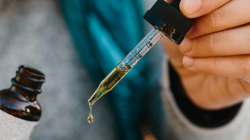 Man using CBD liquid dropper product.